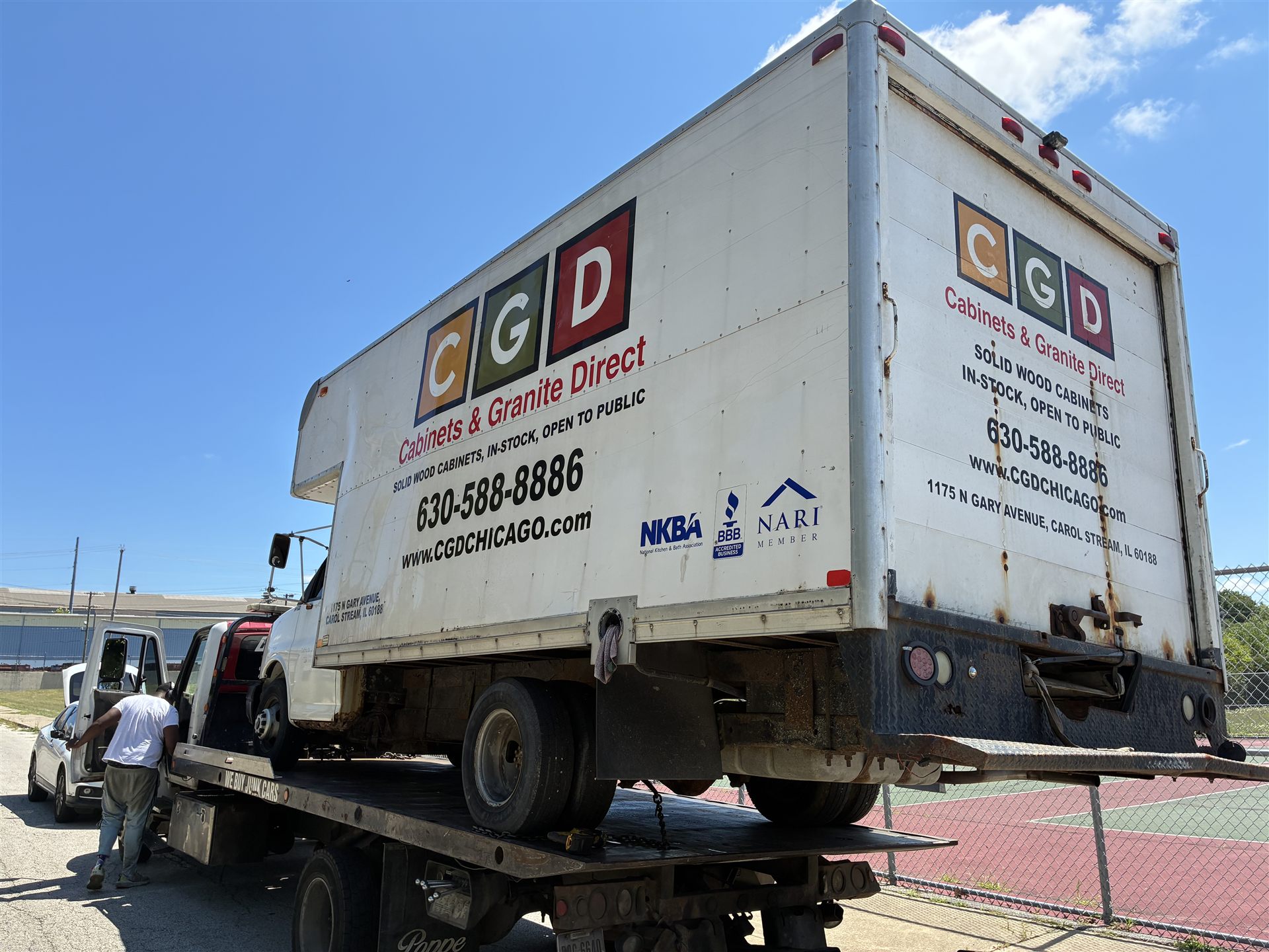 Flatbed tow truck carrying a box truck